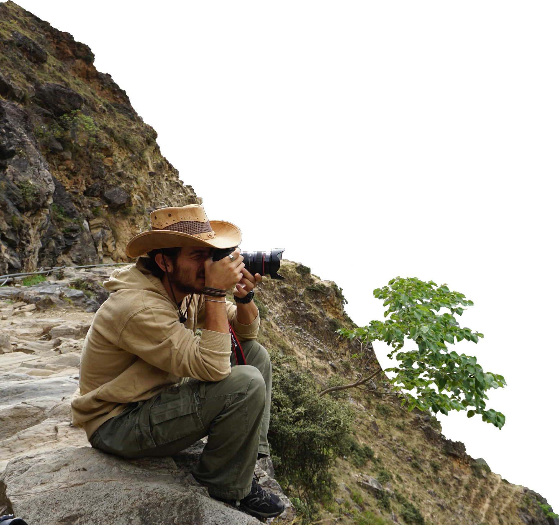 Yonatan Vilan crouched on a mountain path, photographing the valley